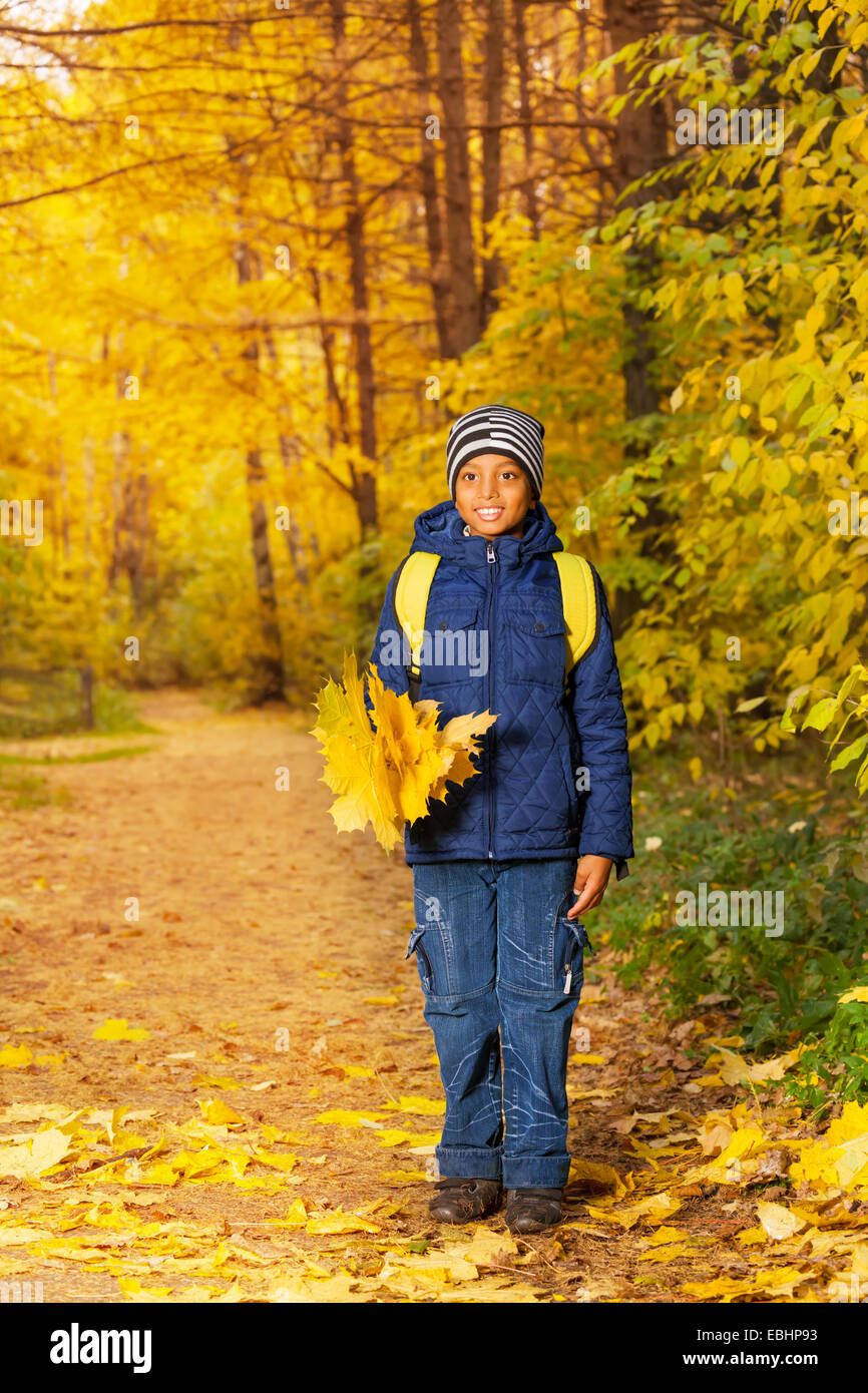 African boy avec tas de feuilles d'érable jaune Banque D'Images