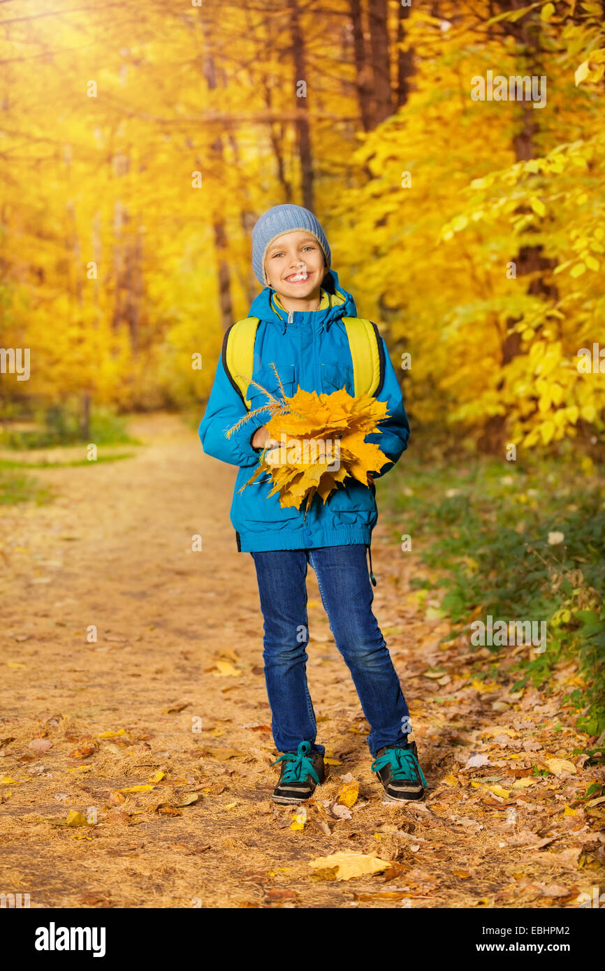 Mignon petit garçon avec des tas de feuilles d'érable jaune Banque D'Images