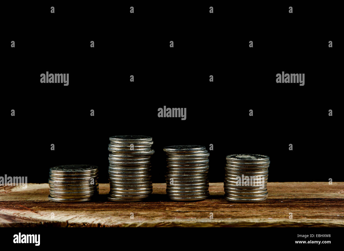 Des piles de pièces d'argent à une vieille table en bois et un fond noir Banque D'Images