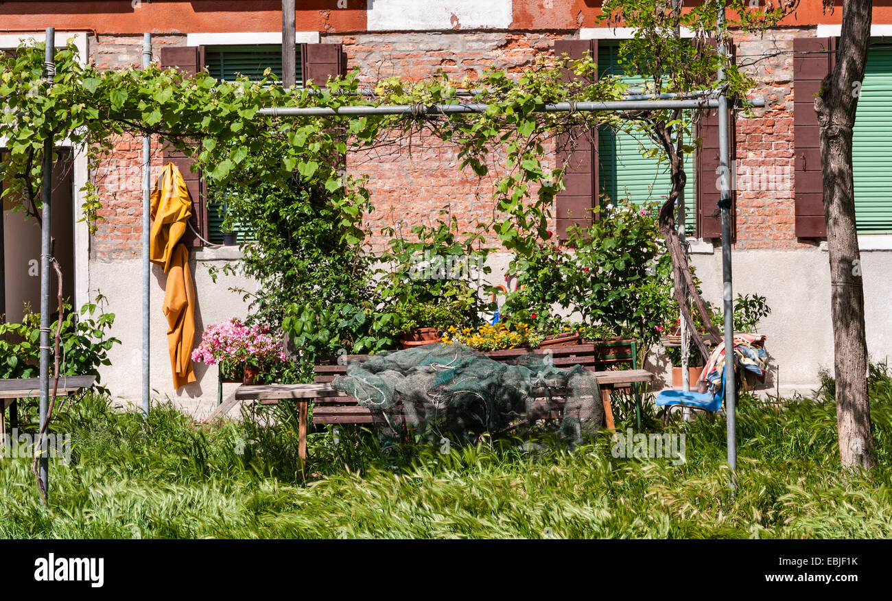 Venise, Italie. Une place tranquille sur l'île de Giudecca, où l'avoine sauvage pousse à travers les pavés et les filets de pêche sont réparés Banque D'Images