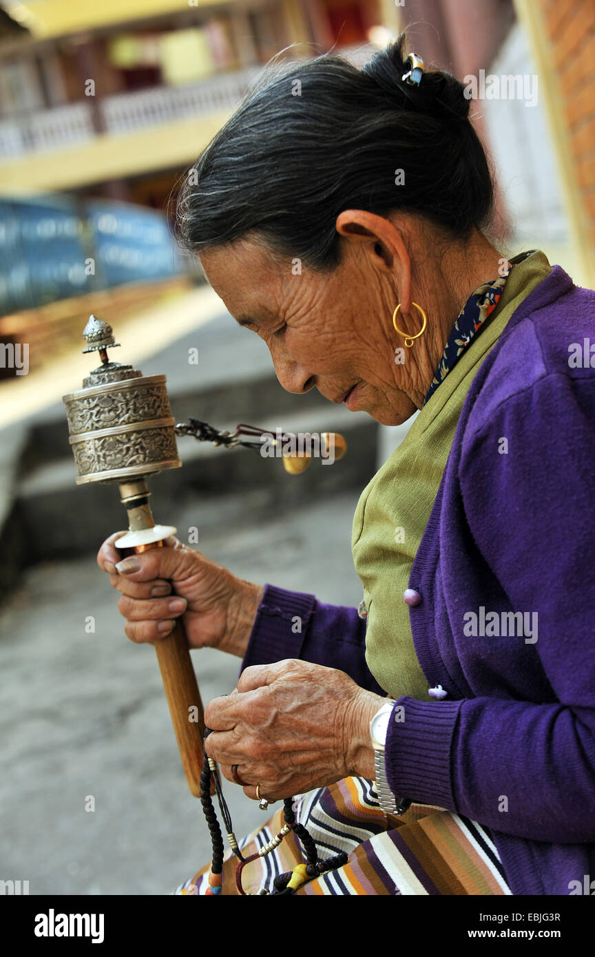Vieille Femme dans un monastère bouddhiste est coulé dans une prière avec un moulin à prières à la main, Népal, Pokhara Banque D'Images