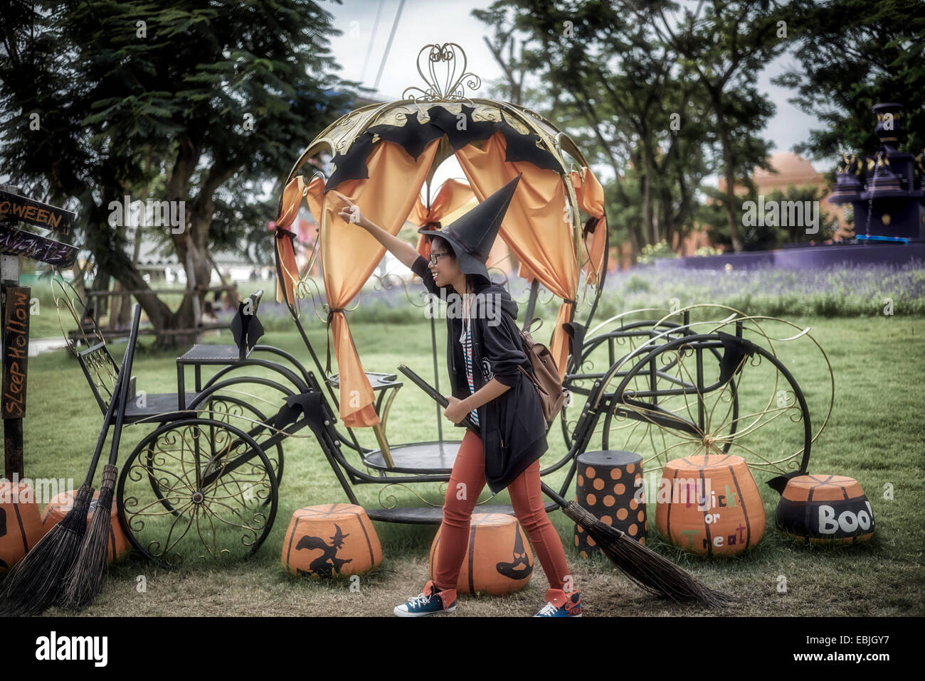Sorcière Halloween. Image humoristique d'une jeune fille contre un ensemble d'Halloween avec un balai de sorcières et un chapeau conique Banque D'Images
