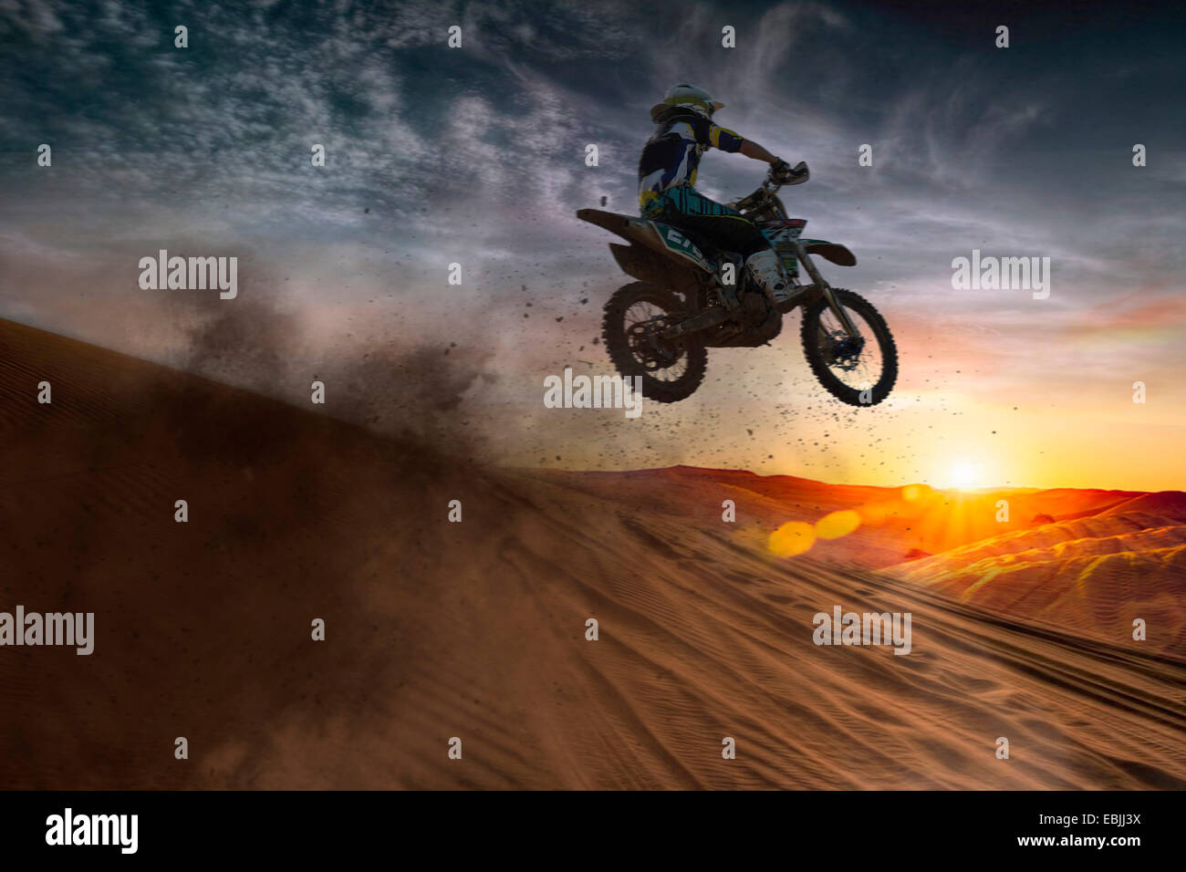 Jeune homme motocross racer jumping mid air au coucher du soleil Banque D'Images