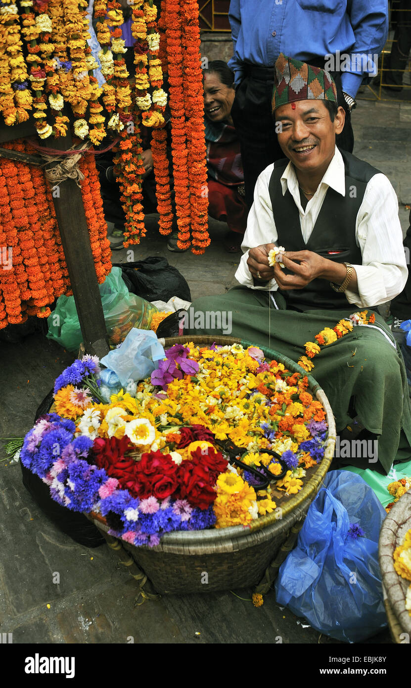L'homme préparer des guirlandes de fleurs d'oranger pour une cérémonie, Népal, Katmandou Banque D'Images
