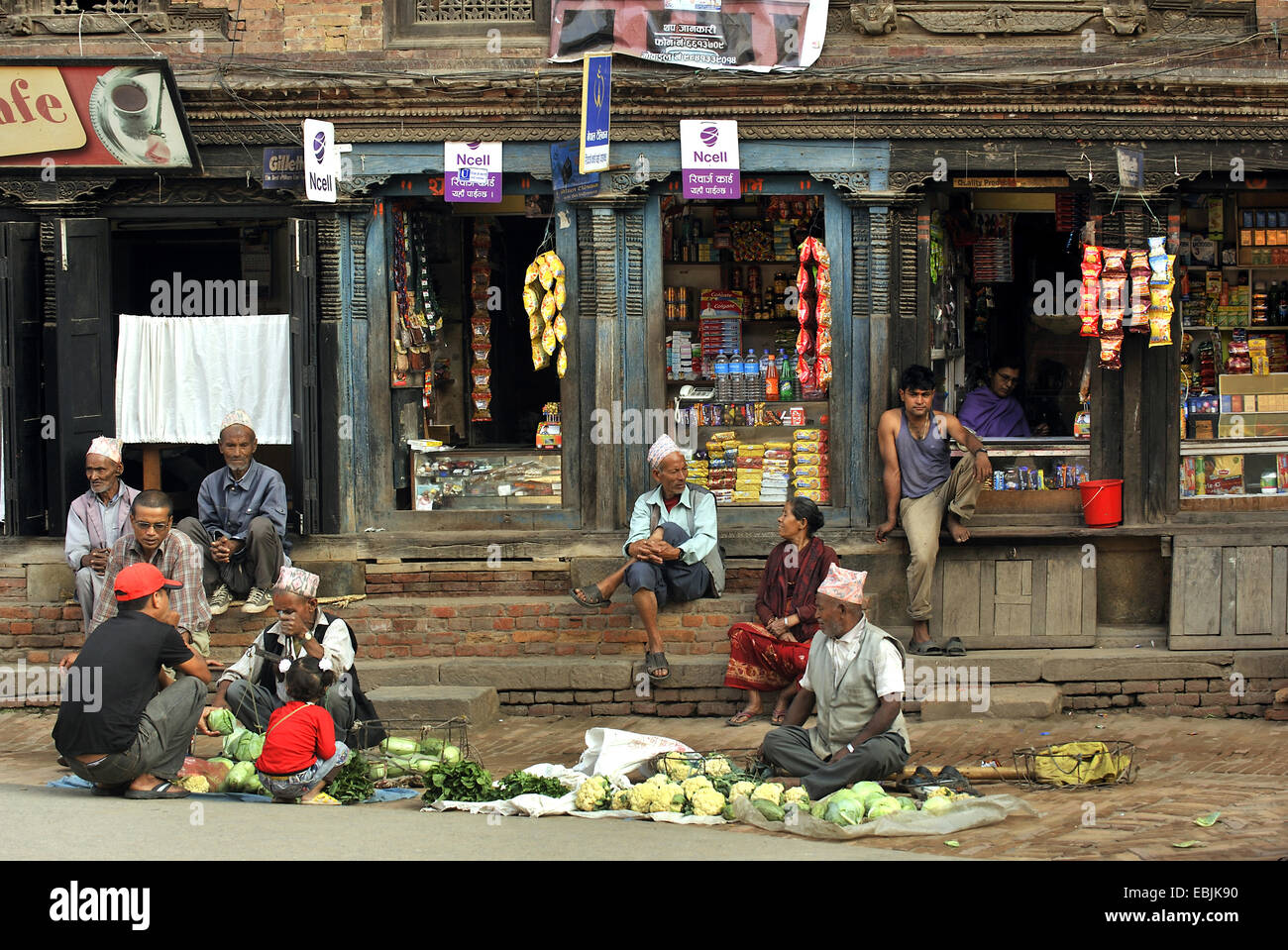 Des gens assis en face de boutiques dans une rue de la petite ville près de Katmandoo, Népal, Patan Banque D'Images