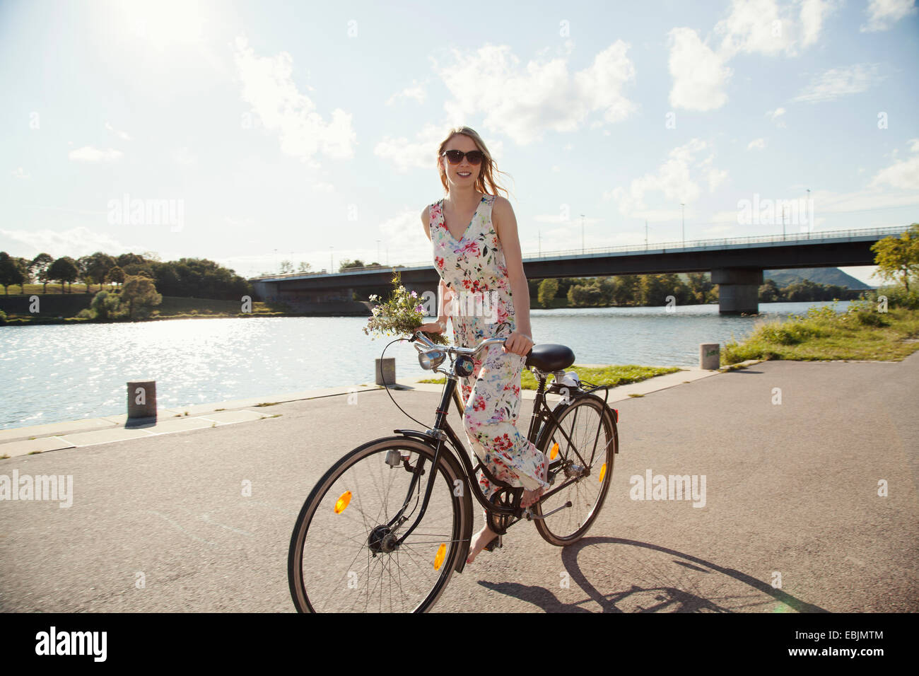 Jeune femme à vélo le long de la rivière, l'île du Danube, Vienne, Autriche Banque D'Images