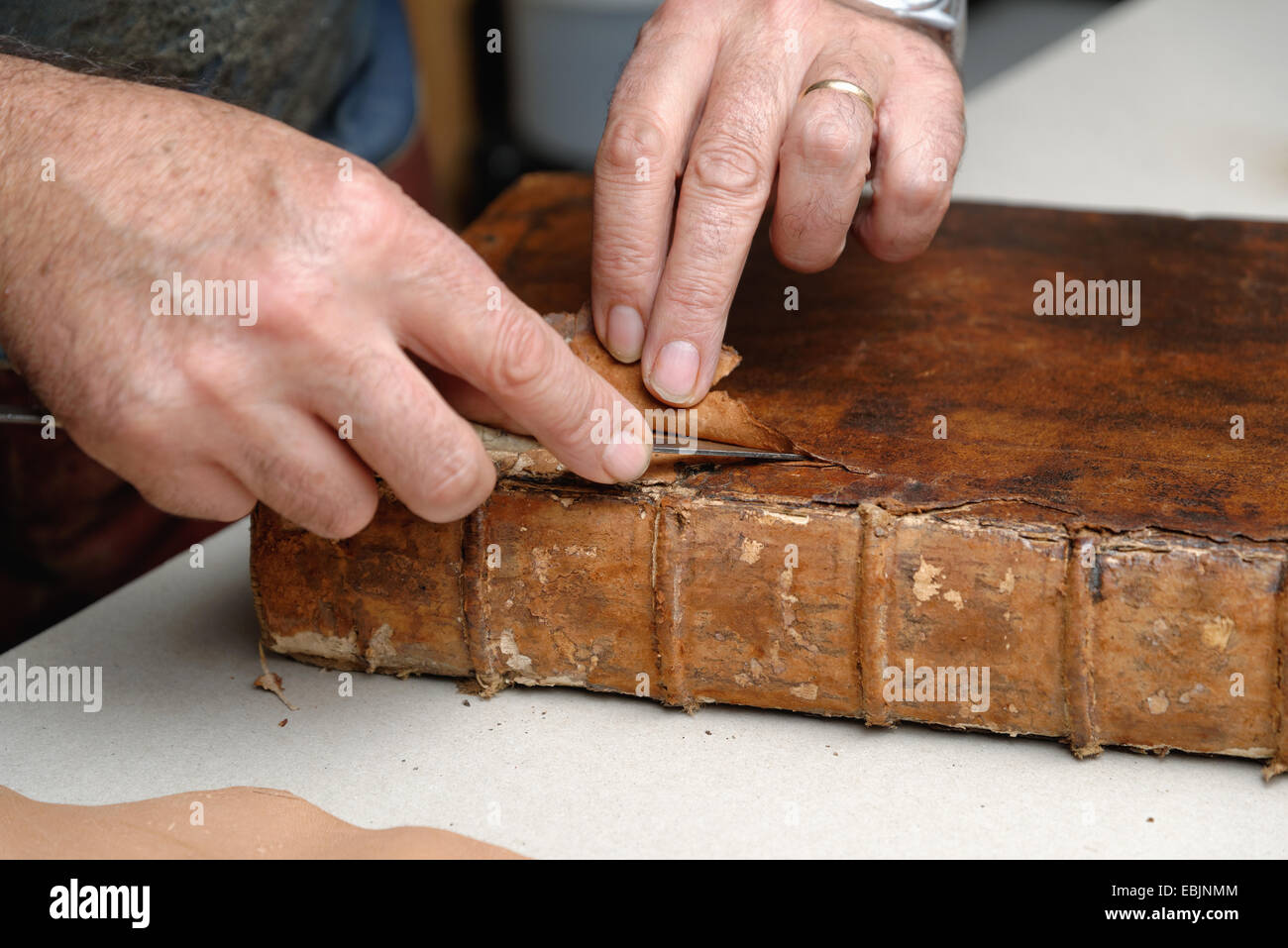Close up of hands of senior male relieur traditionnel en cuir à partir de la suppression d'adresses Banque D'Images