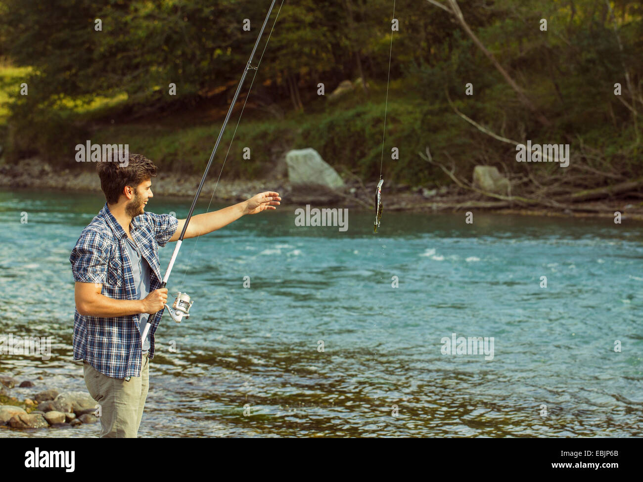 Jeune homme la capture de poissons dans la rivière, Premosello, Verbania, Piemonte, Italie Banque D'Images