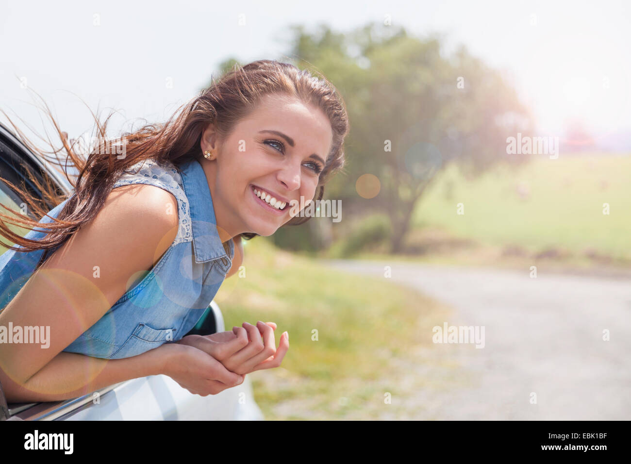 Young woman leaning out of car window on road trip Banque D'Images
