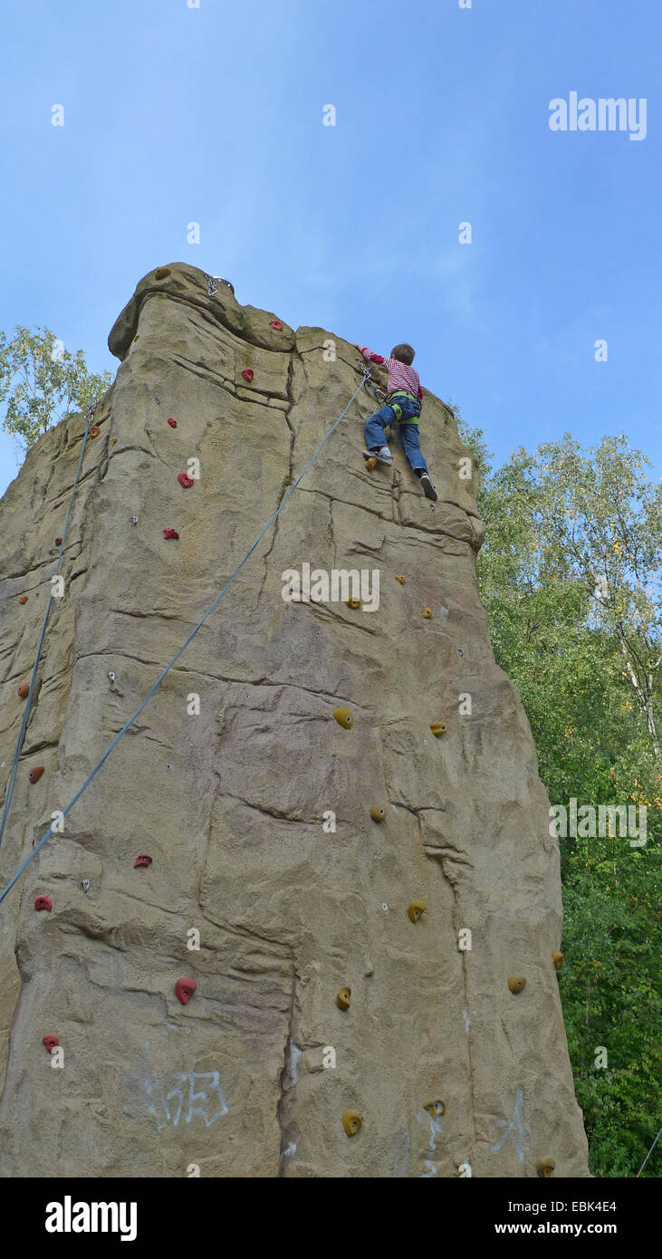 Petit garçon escalade encordés dans un mur d'escalade professionnel Banque D'Images