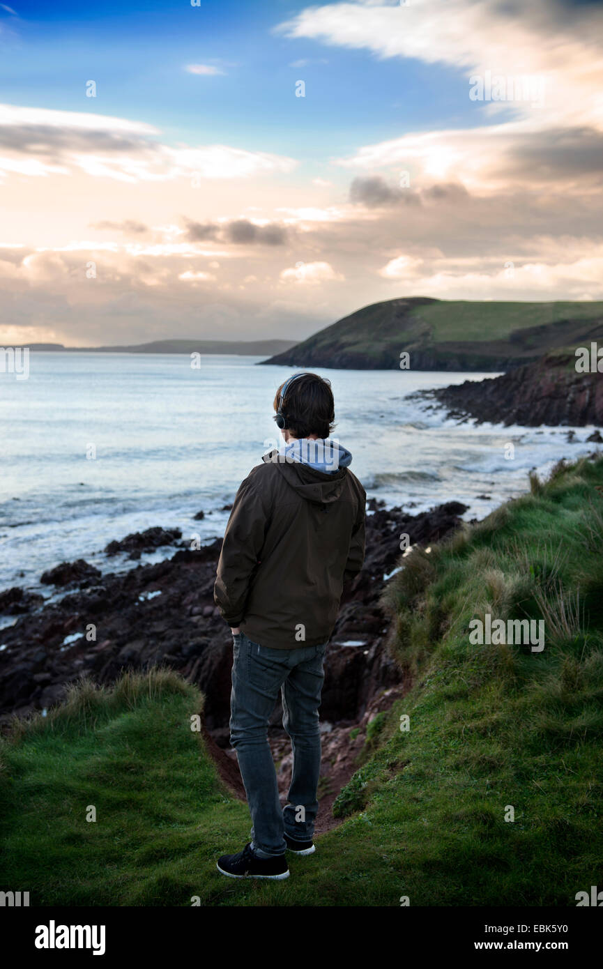 Un adolescent écoute son iPod tout en regardant la vue sur la baie de Tenby Tenby dans près de Pembrokeshire, Pays de Galles UK Banque D'Images