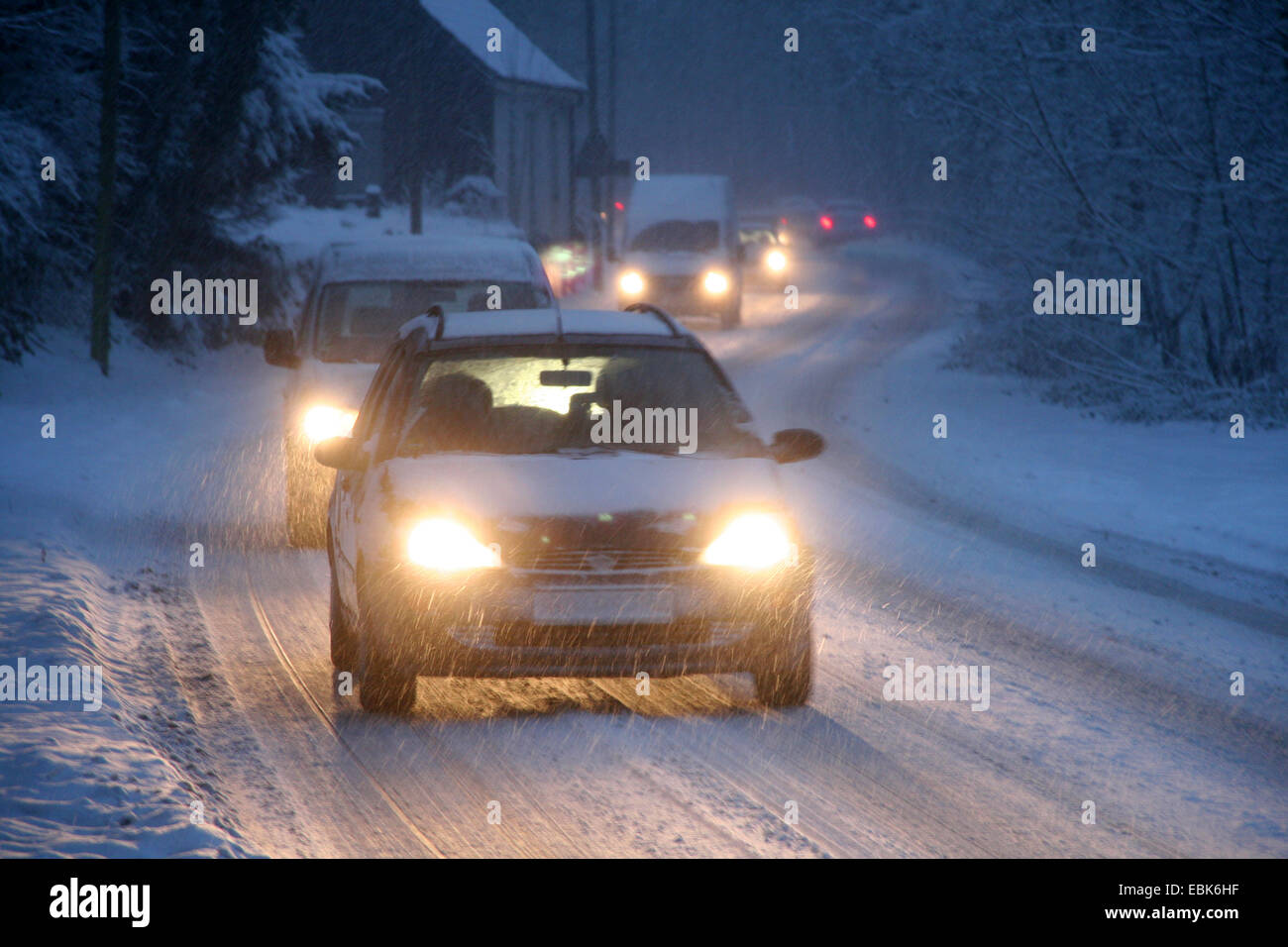 Le trafic lent on a snowy street dans la soirée, l'Allemagne, Rhénanie du Nord-Westphalie Banque D'Images