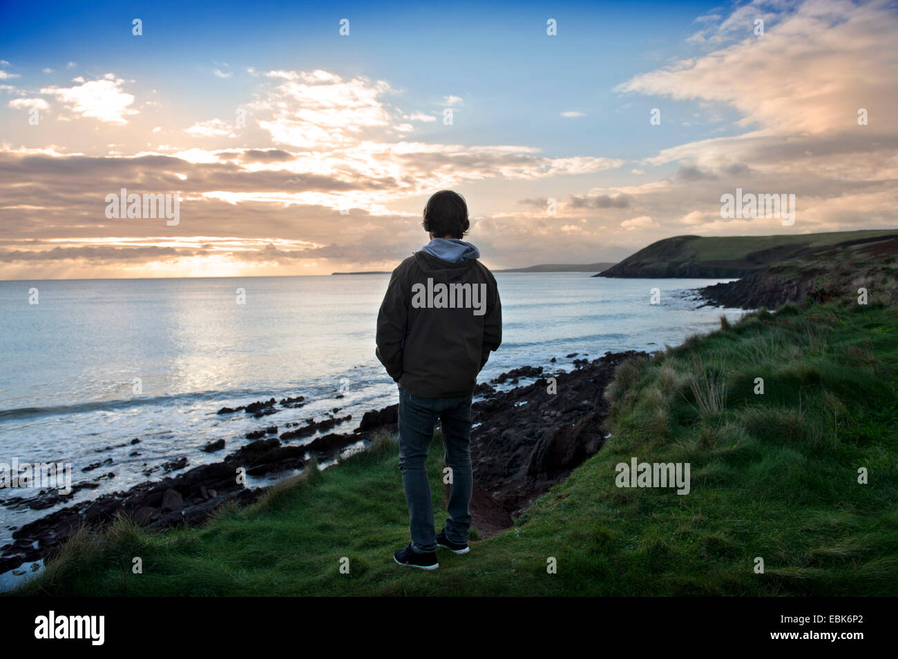 Un adolescent écoute son iPod tout en regardant la vue sur la baie de Tenby Tenby dans près de Pembrokeshire, Pays de Galles UK Banque D'Images