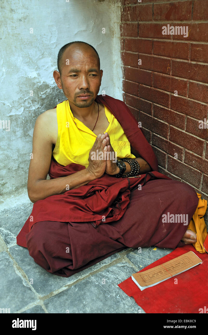 Un moine assis en prière sur le sol dans un coin de la stupa de Bouddhanath, l'un des sites bouddhistes les plus sacrés du pays, le Népal, Bodnath, Katmandou Banque D'Images