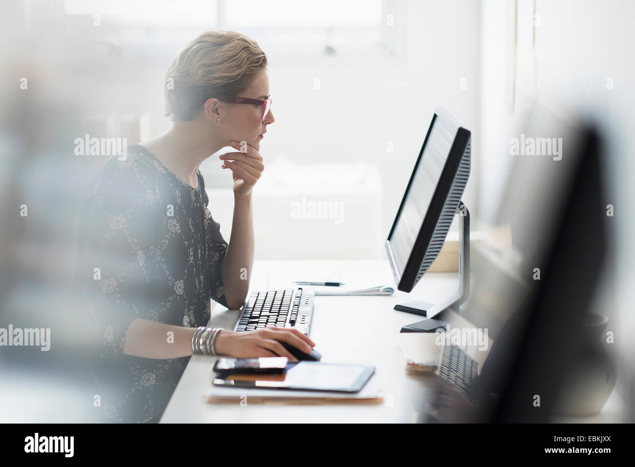 Vue de côté business woman working on desktop pc in office Banque D'Images
