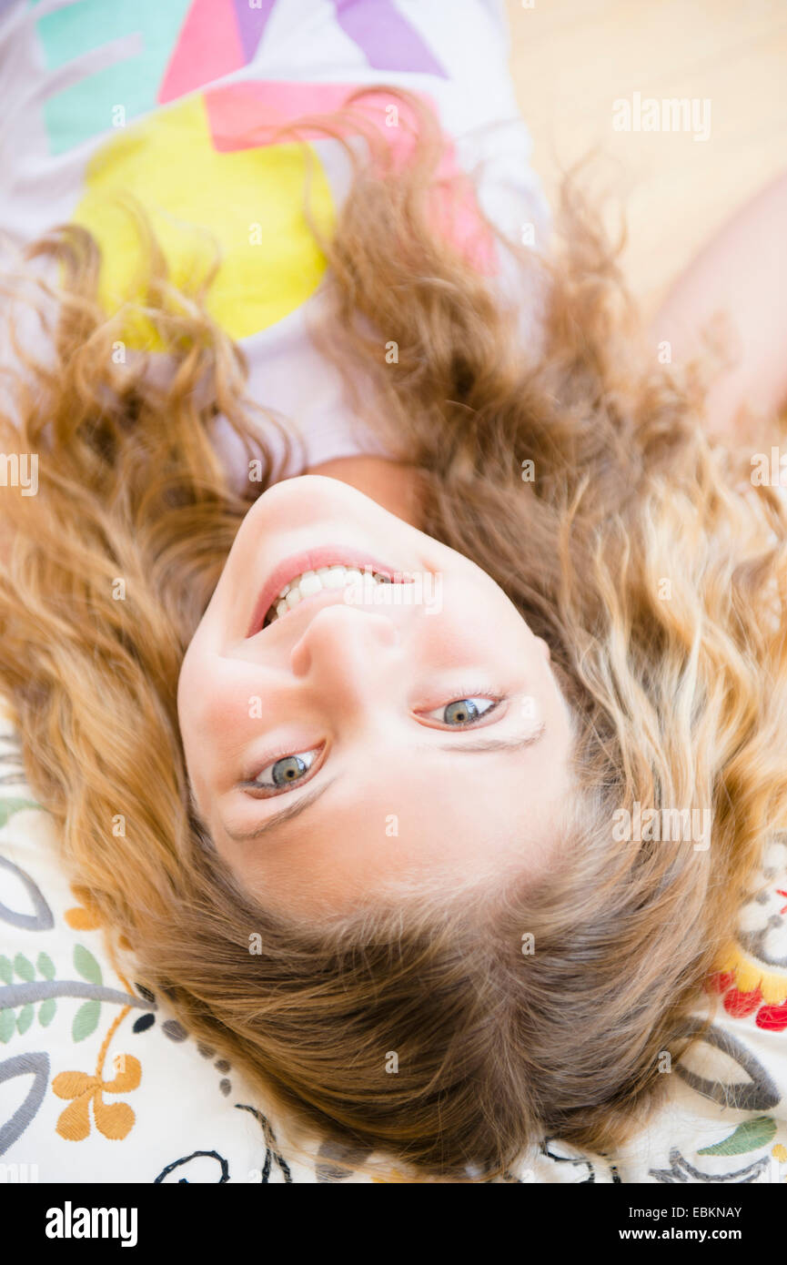 Portrait of smiling teenage girl (12-13) lying on pillow Banque D'Images