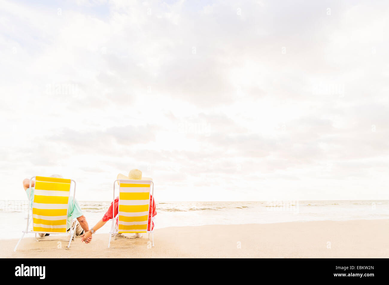 USA, Floride, Jupiter, vue arrière du couple assis dans des chaises longues sur la plage Banque D'Images
