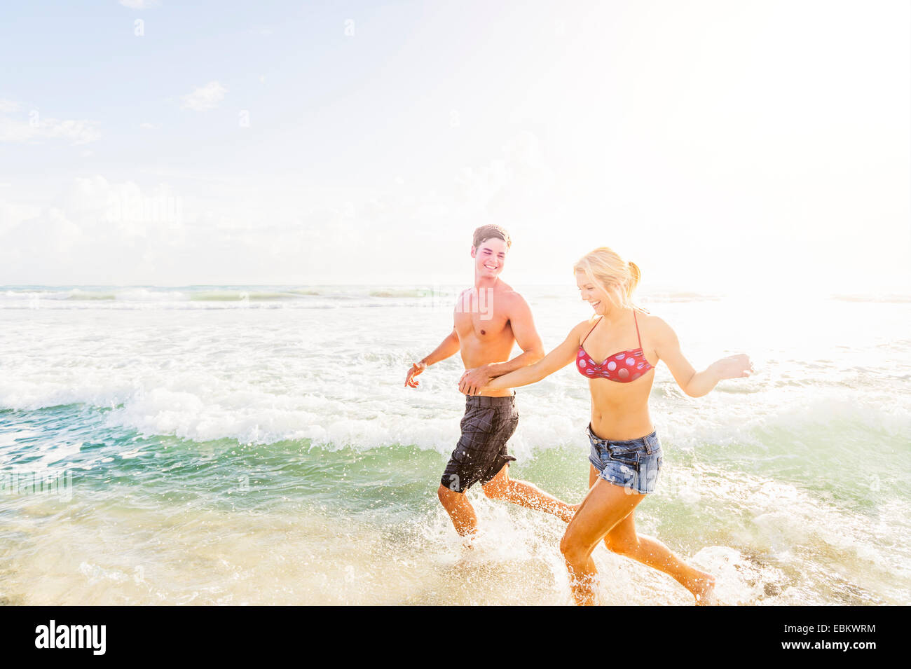 USA, Floride, Jupiter, jeune couple running in surf holding hands Banque D'Images