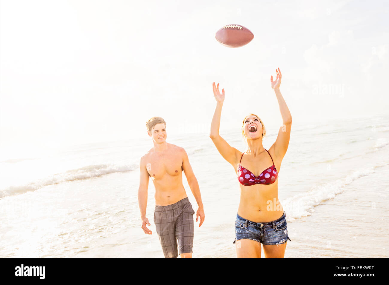 USA, Floride, Jupiter, jeune femme attraper football on beach Banque D'Images