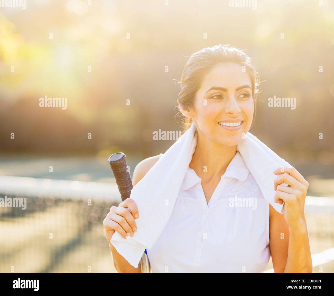 Portrait of smiling young woman with towel et raquette de tennis Banque D'Images