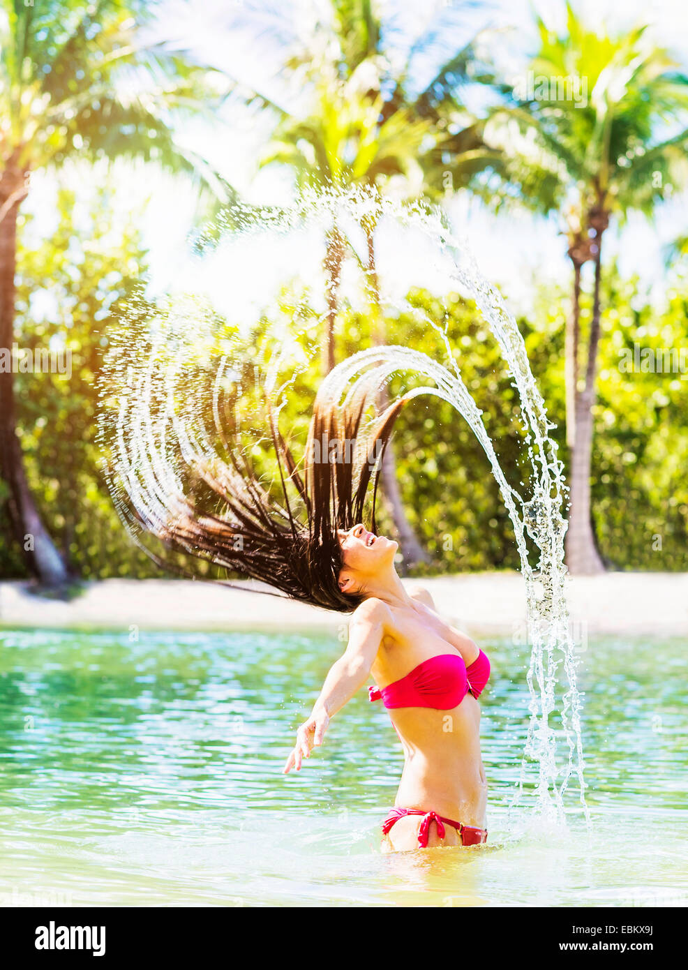 USA, Floride, Jupiter, Portrait of young woman wearing bikini tossing sèche et aux projections d'eau dans le lagon tropical Banque D'Images