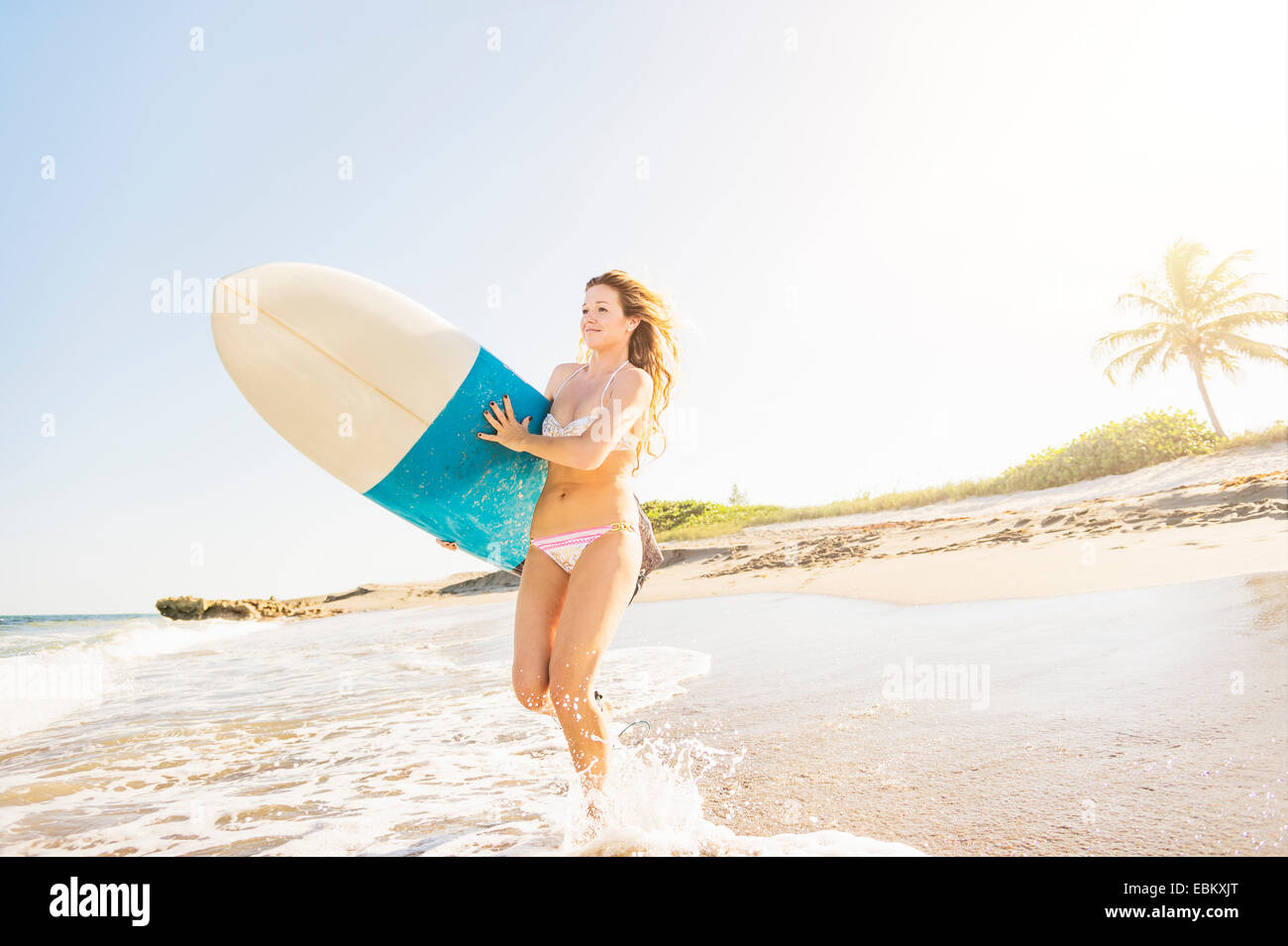 USA, Floride, Jupiter, young woman running in surf surfboard comptable dans la mer Banque D'Images