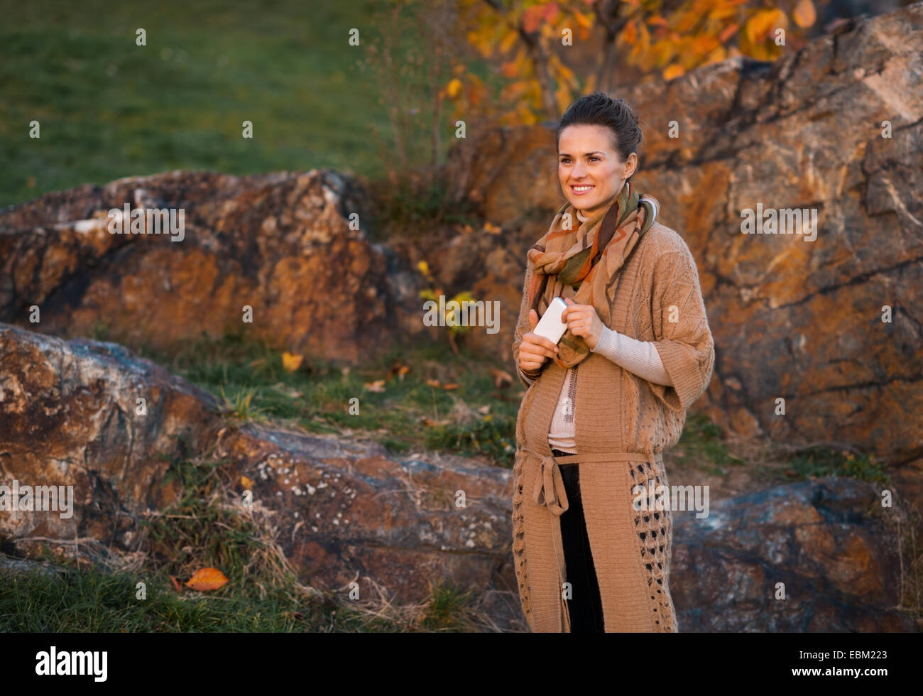 Jeune femme avec téléphone cellulaire en plein air le soir d'automne Banque D'Images