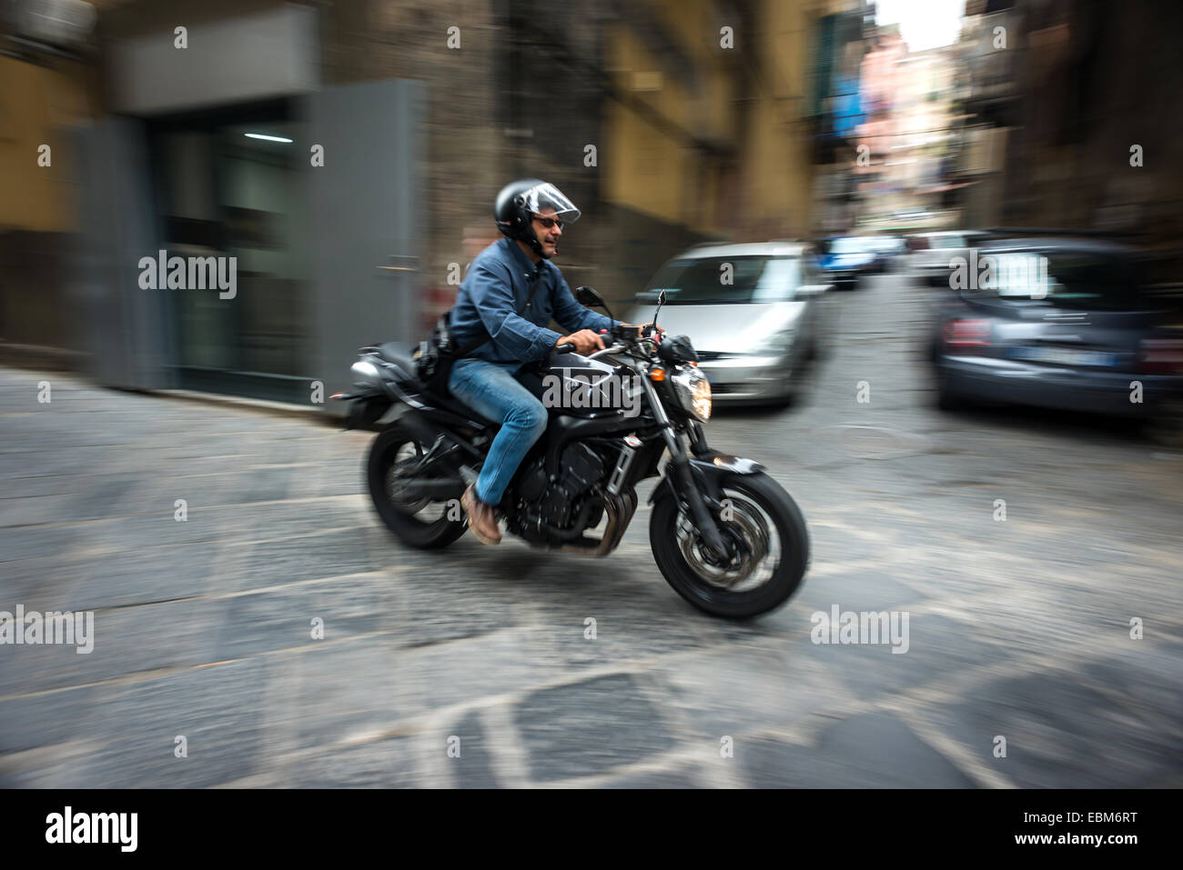 Un motocycliste équitation à travers les petites rues de Naples. Banque D'Images