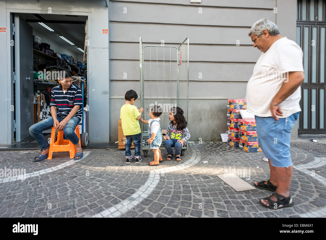 Un trader veille sur sa famille à l'extérieur d'un magasin à Naples. Banque D'Images