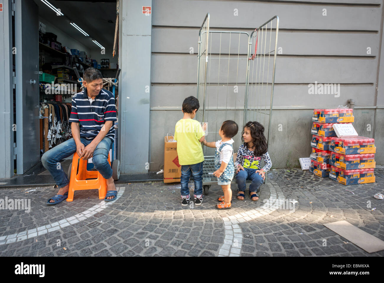 Un trader veille sur sa famille à l'extérieur d'un magasin à Naples. Banque D'Images