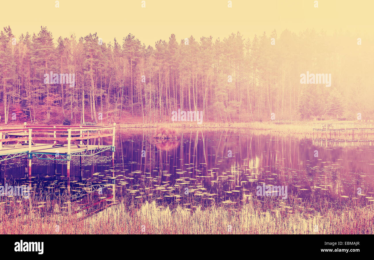 Vintage photo filtrée en bois de la jetée du lac au coucher du soleil. Banque D'Images