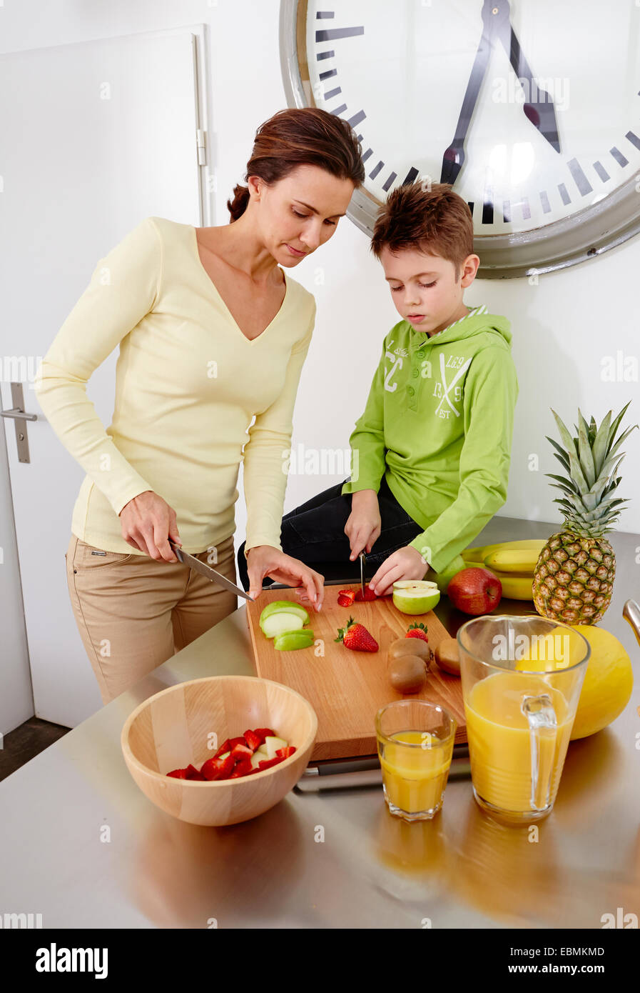 Mère et fils couper divers types de fruits sur une planche à découper dans une cuisine, Allemagne Banque D'Images