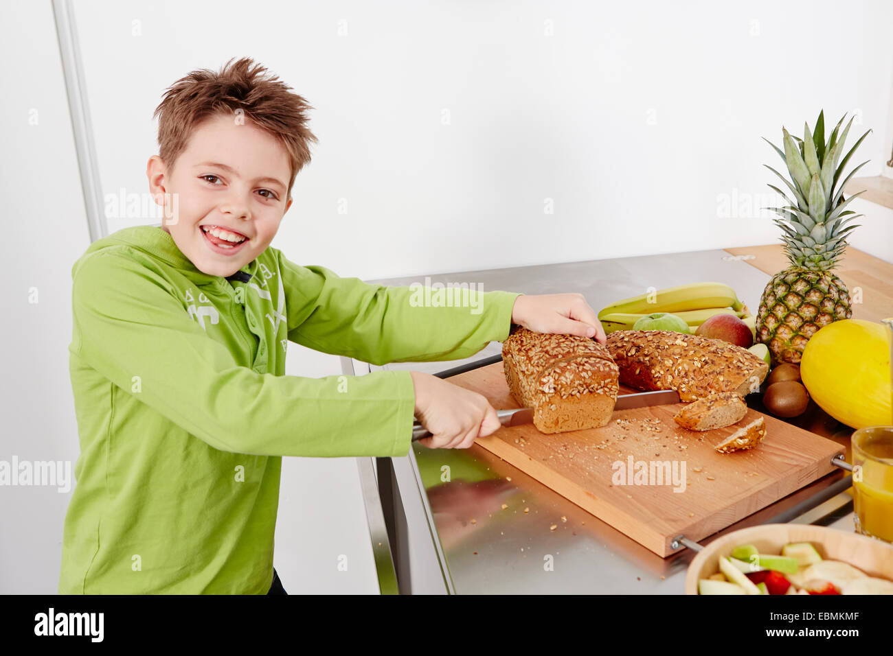 Coupe garçon coupe un pain de blé entier, Allemagne Banque D'Images