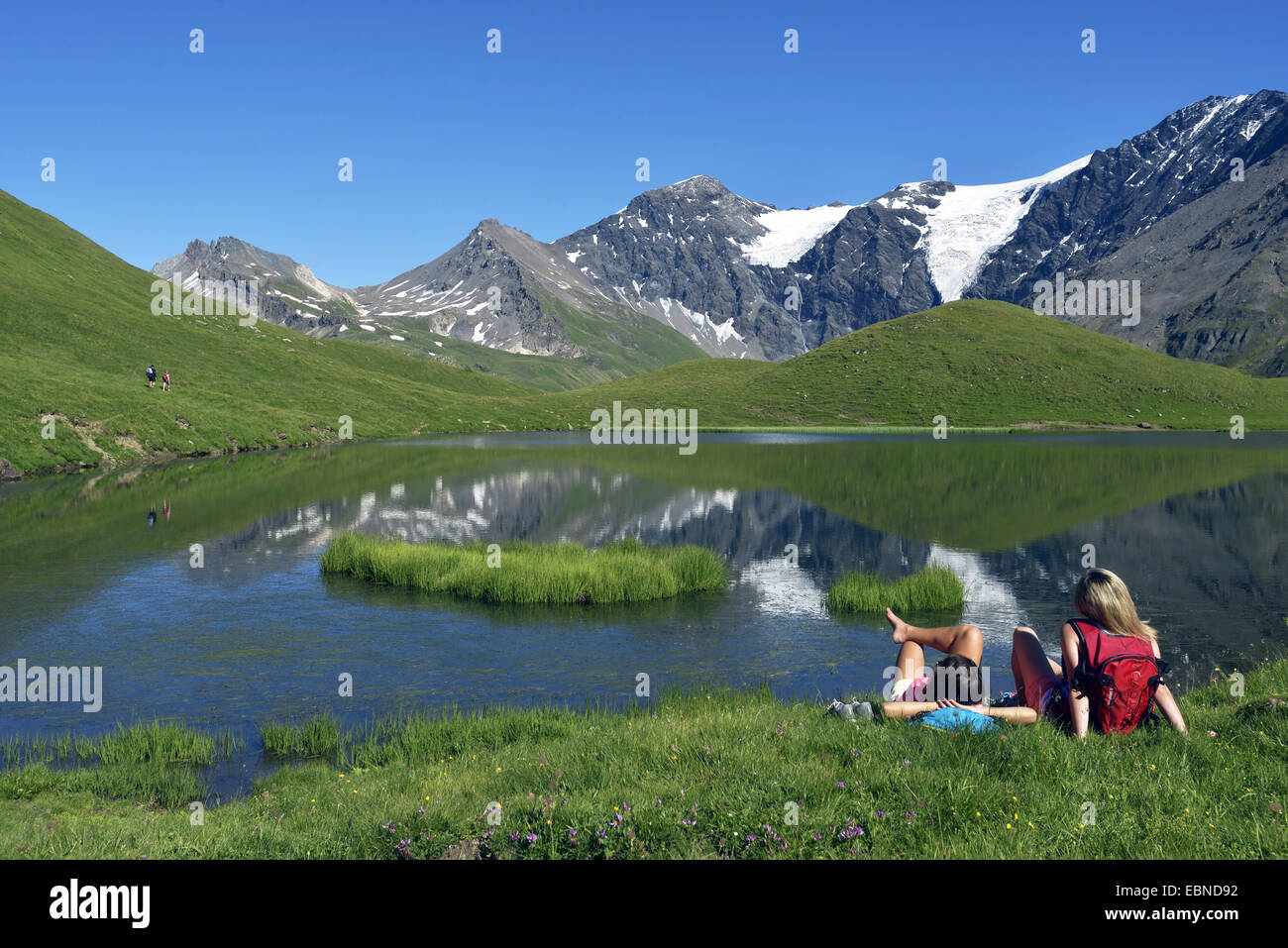 Deux adolescents assis dans la prairie de montagne et profiter de la vue de lac de montagne, France, Savoie, Sainte-Foy Tarentaise Banque D'Images