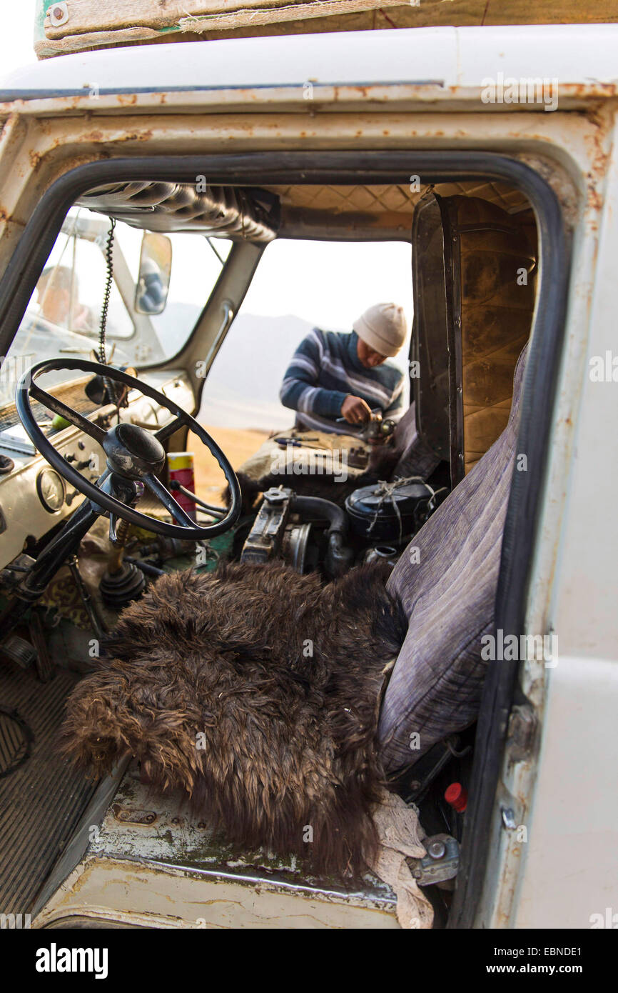 Vue de la cabine du conducteur, l'homme de réparer un vieux camion soviétique, le Kirghizstan, Naryn Banque D'Images