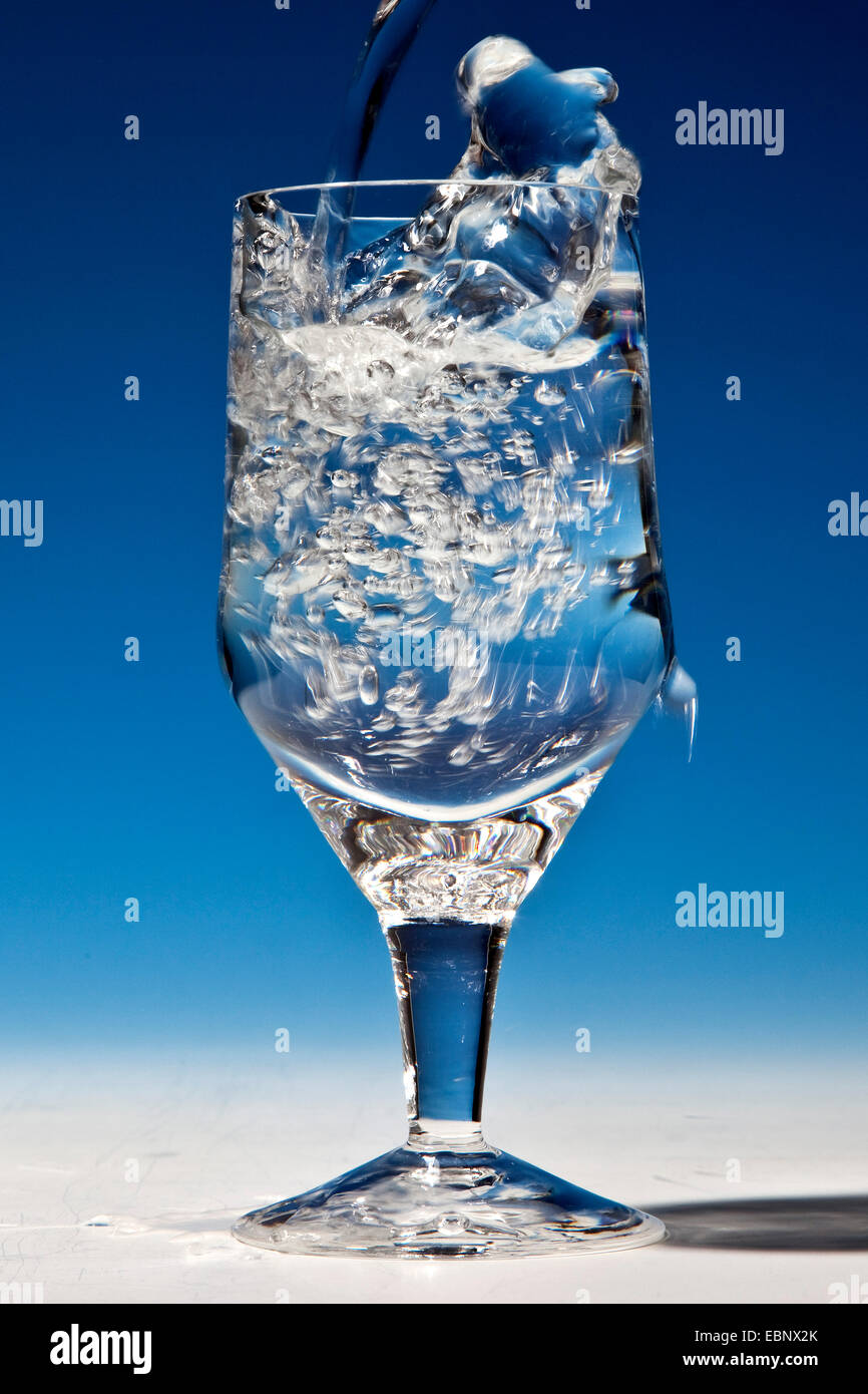 L'eau minérale est versé dans un verre à boire Banque D'Images