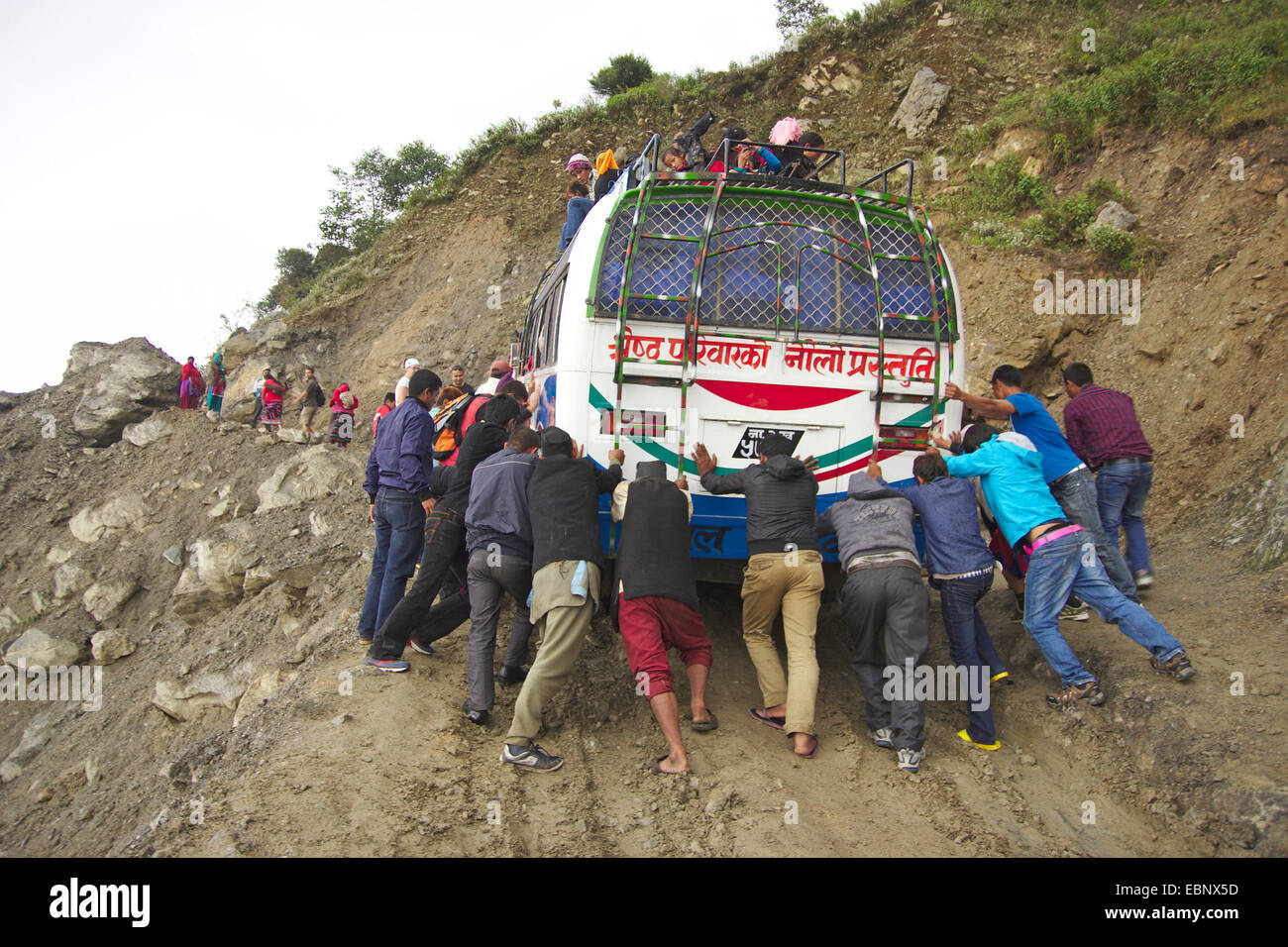 Personnes poussant un bus sur une route boueuse sur le chemin à Dhunche, Népal, Langtang Himal Banque D'Images