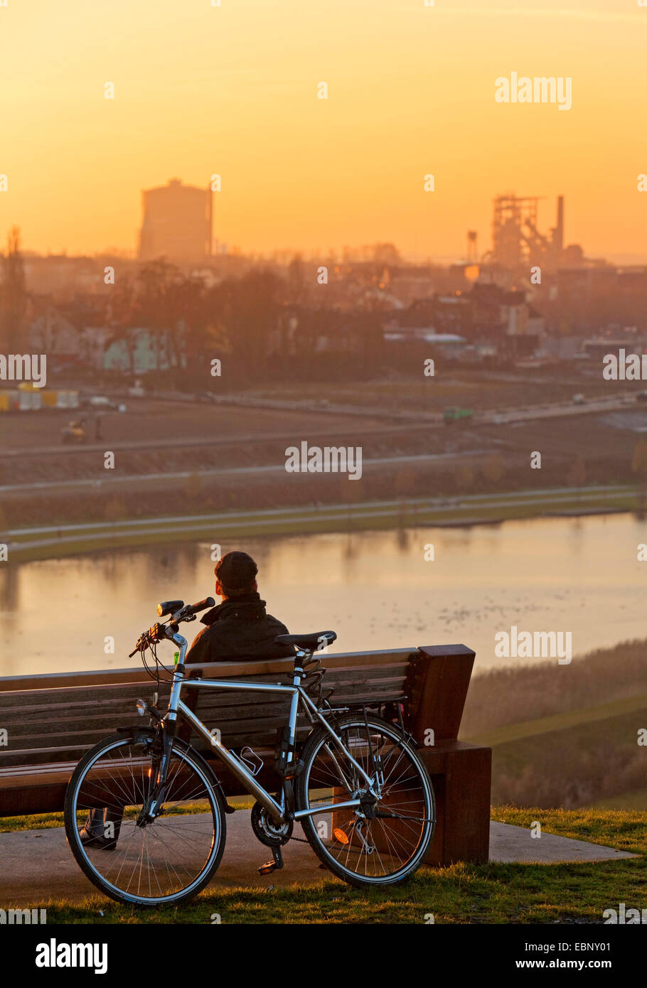 Cycliste assis sur un banc, avoir une pause et profiter du coucher du soleil à Lake Phoenix, l'Allemagne, en Rhénanie du Nord-Westphalie, Ruhr, Dortmund Banque D'Images