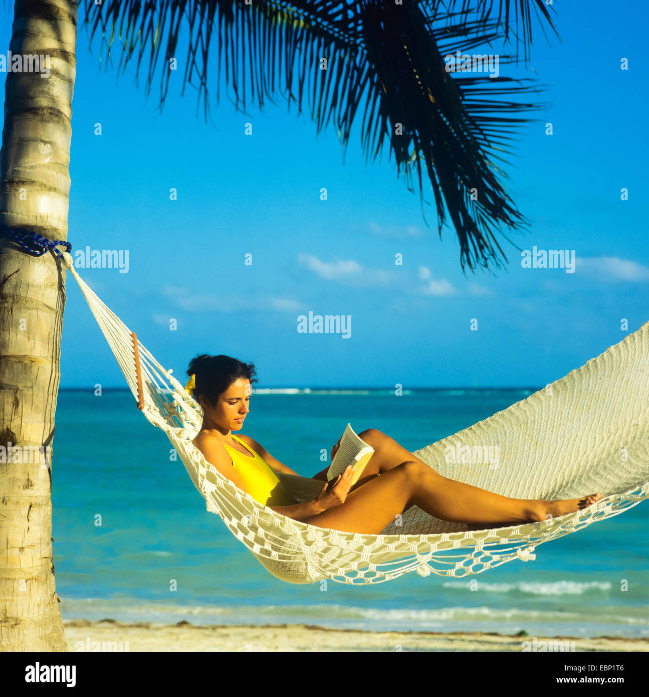 Jeune femme lisant un livre en hamac sur la plage des Caraïbes Guadeloupe Antilles Françaises Petites Antilles Banque D'Images