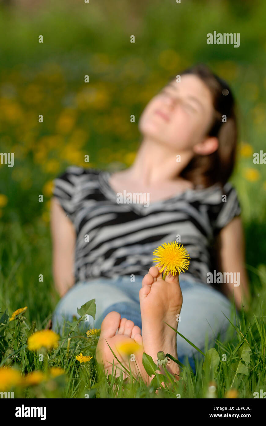 Jeune femme couchée dans une prairie pissenlit printemps profiter du soleil, de l'Allemagne Banque D'Images
