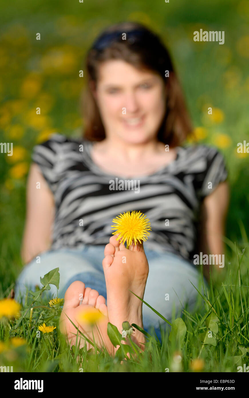 Jeune femme couchée dans une prairie pissenlit printemps profiter du soleil, de l'Allemagne Banque D'Images