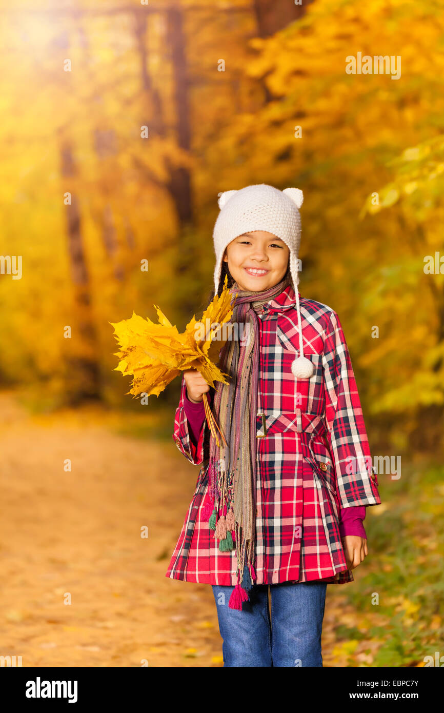 Cheerful Asian girl avec des tas de feuilles jaunes Banque D'Images