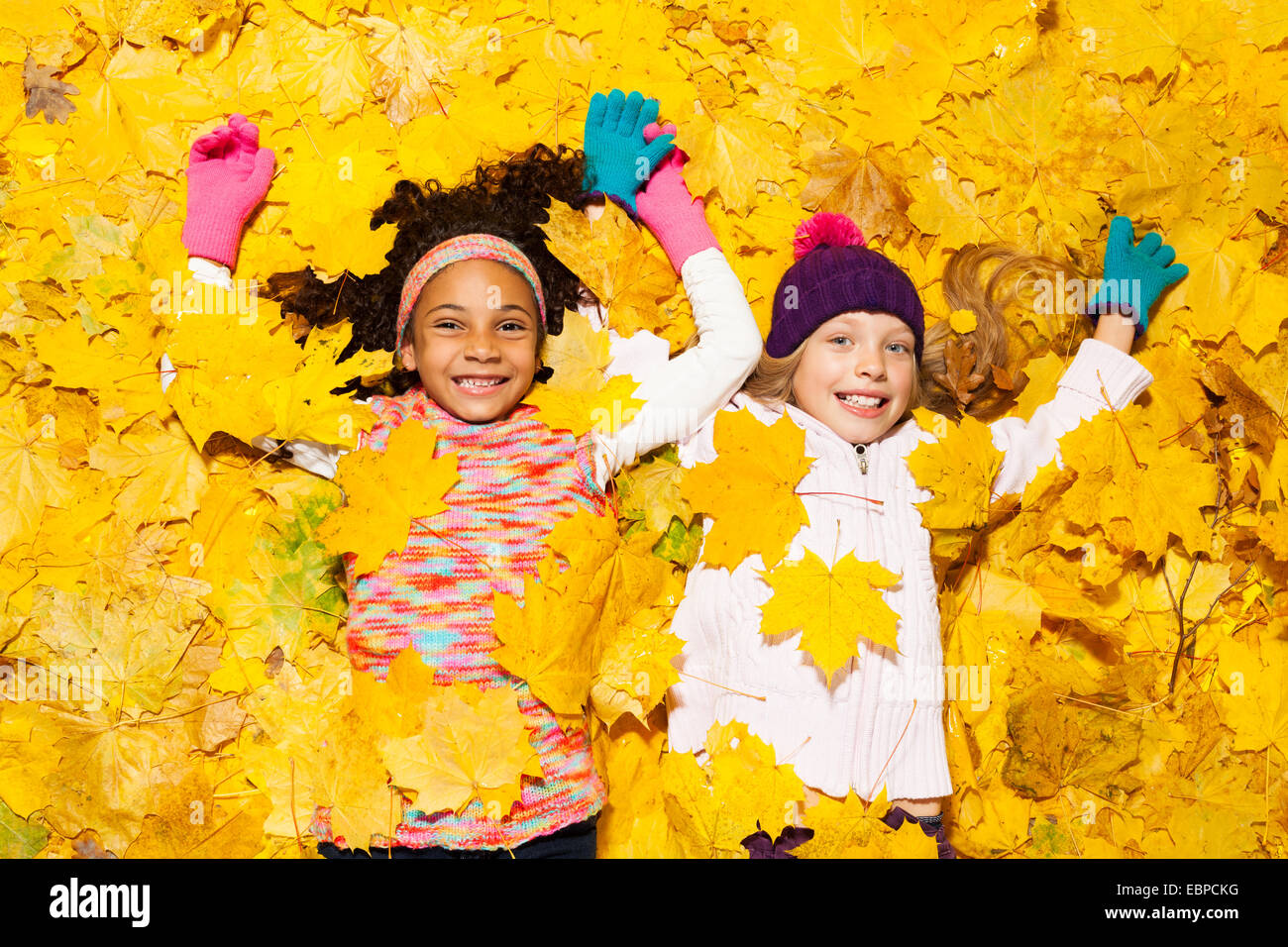 African and Caucasian girl couvert de feuilles d'érable Banque D'Images