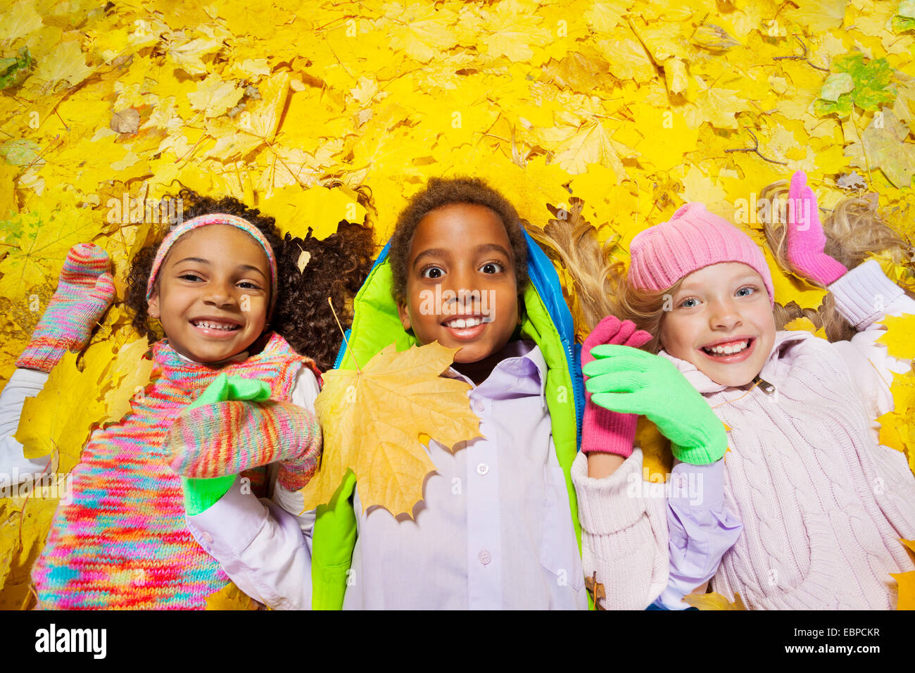 Groupe de garçon et filles dans les feuilles d'automne Banque D'Images