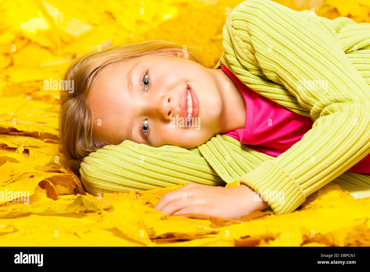 Petite fille blonde se pose sur l'automne feuilles d'érable Banque D'Images