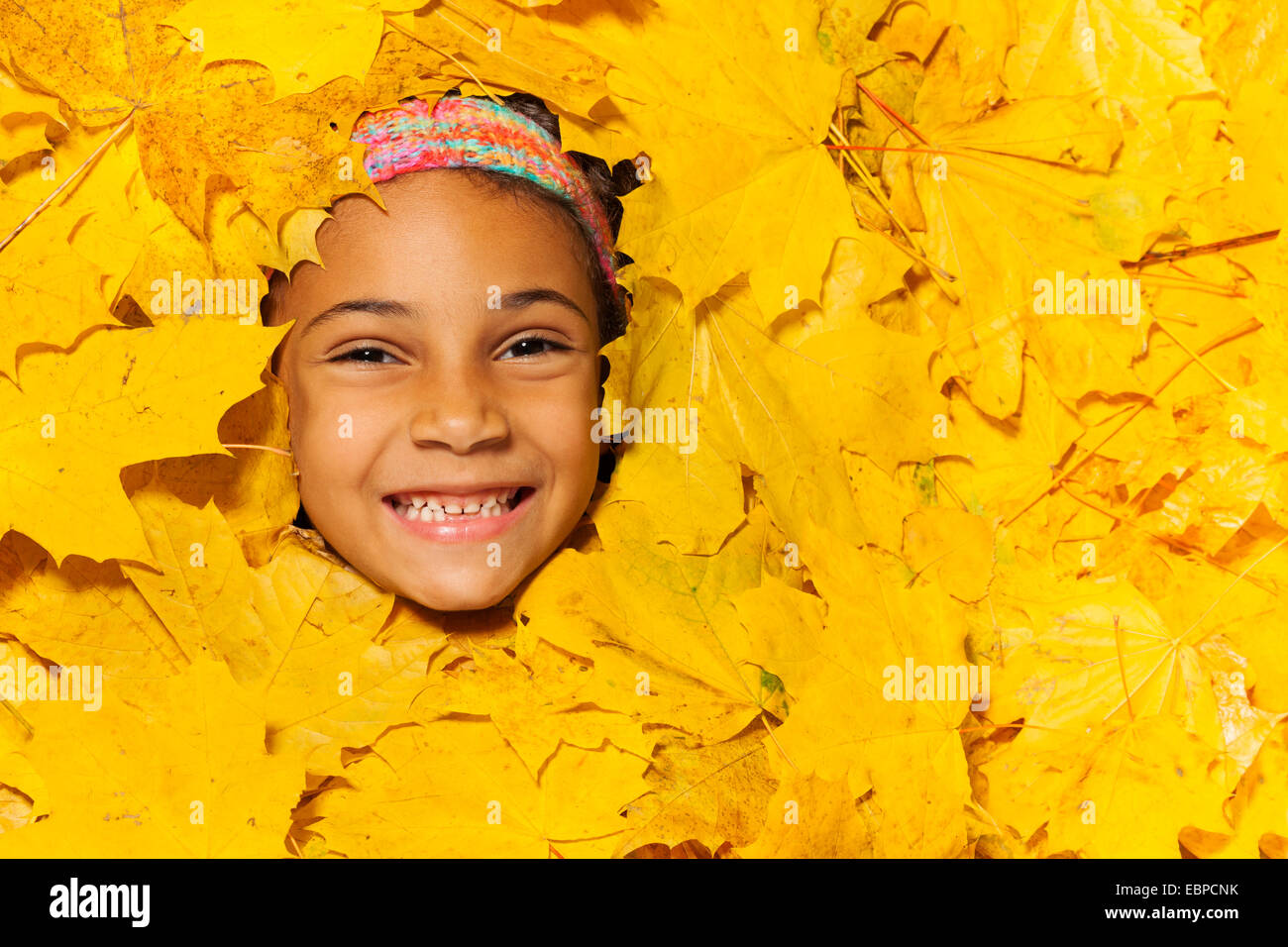 Visage d'une petite fille africaine dans les feuilles d'automne Banque D'Images