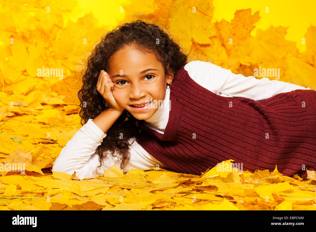 Petite fille noire se pose sur l'automne feuilles d'érable Banque D'Images