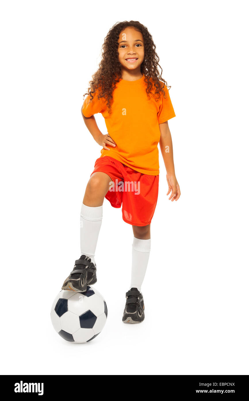 Cute girl noir debout sur un ballon de football en studio Banque D'Images