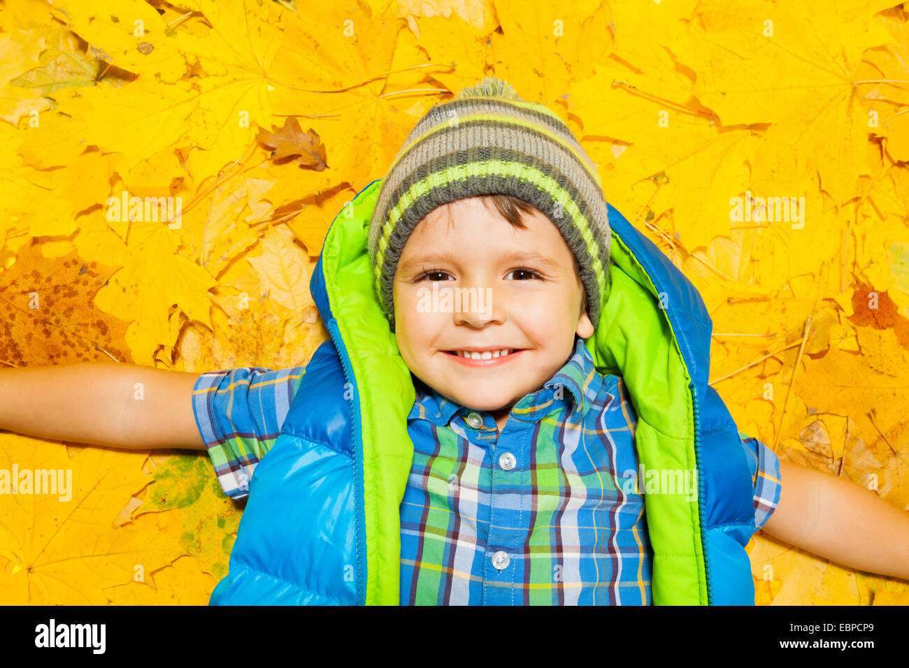 Happy boy laying in orange et feuilles jaunes Banque D'Images