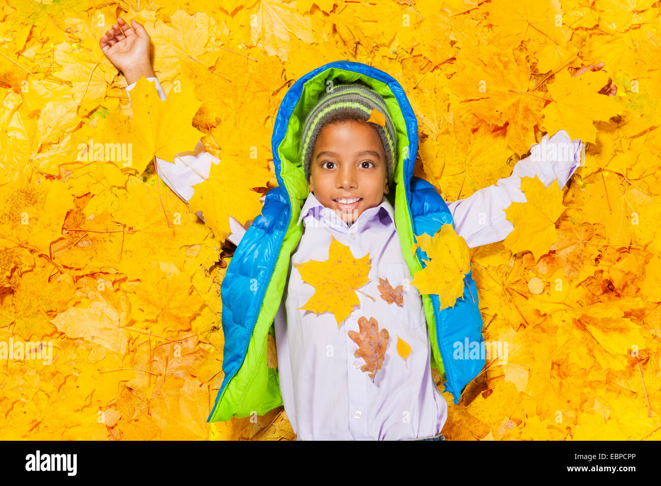 African boy laying in automne feuilles d'érable Banque D'Images